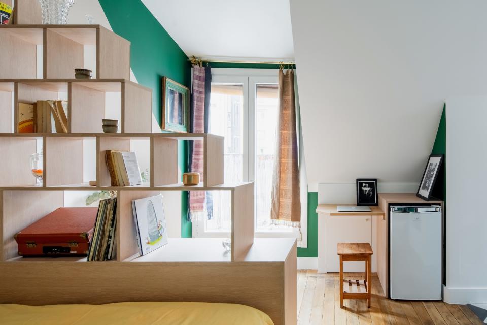 The library around the bed was designed as a "book nest," where geometric modules create a separation between the bed and the large, main window.