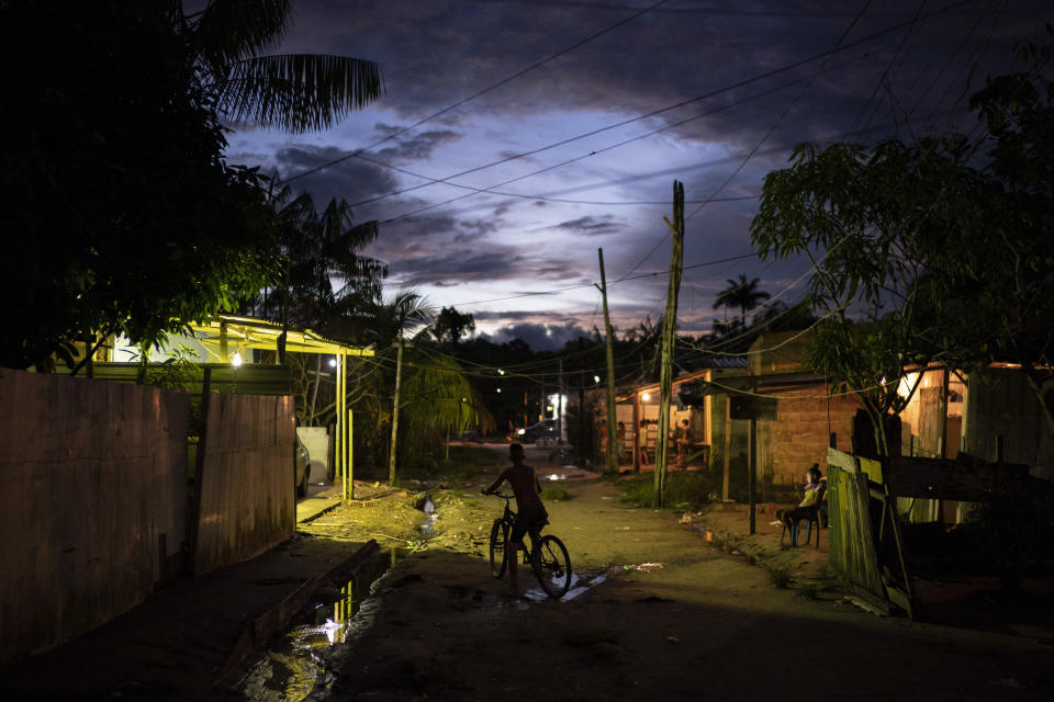 Un niño monta en bicicleta al atardecer en la comunidad Parque de Naciones Indígenas, donde muchos residentes cayeron enfermos con síntomas del nuevo coronavirus, en Manaos, Brasil, el 10 de mayo de 2020. Per cápita, Manaos es la ciudad de Brasil más golpeada por el COVID-19. (AP Foto/Felipe Dana)