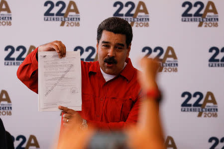 President Nicolas Maduro holds a document as he registers his candidacy for re-election at the National Electoral Council (CNE) headquarters in Caracas, Venezuela February 27, 2018. REUTERS/Marco Bello