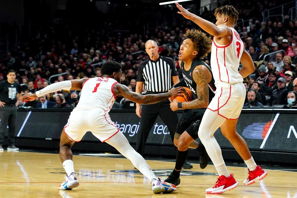 Cincinnati Bearcats guard Jeremiah Davenport (24) drives to the basket as Houston Cougars guard Jamal Shead (1) and Houston Cougars guard Taze Moore (4) defend in the first half of an NCAA menÕs college basketball game, Sunday, Feb. 6, 2022, at Fifth Third Arena in Cincinnati.