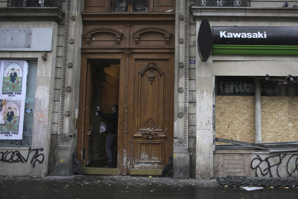 A man cleans a building door after Thursday's violence, Friday, Dec. 6, 2019 in Paris. Frustrated travelers are meeting transportation chaos around France for a second day, as unions dig in for what they hope is a protracted strike against government plans to redesign the national retirement system. (AP Photo/Rafael Yaghobzadeh)