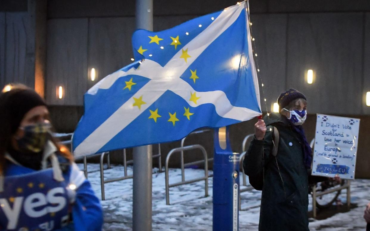 An anti-Brexit pro-Scottish independence activist holds a flag mixing the EU flag - ANDY BUCHANAN/AFP