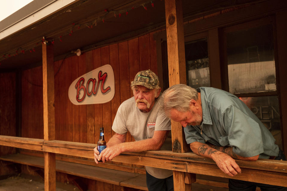 Dave Ferner, left, and Bob Prary watch as multiple homes burn in central Doyle, Calif., as the Sugar Fire, part of the Beckwourth Complex Fire, tears through town on Saturday, July 10, 2021. Ferner said he saved his home using a bulldozer earlier in the day and Prary lost his ranch to a wildfire in November 2020. (AP Photo/Noah Berger)