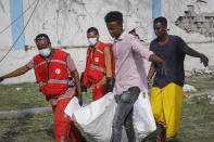 Rescue workers carry away the body of a civilian who was killed in a blast in Mogadishu, Somalia Thursday, Nov. 25, 2021. Witnesses say a large explosion has occurred in a busy part of Somalia's capital during the morning rush hour. (AP Photo/Farah Abdi Warsameh)