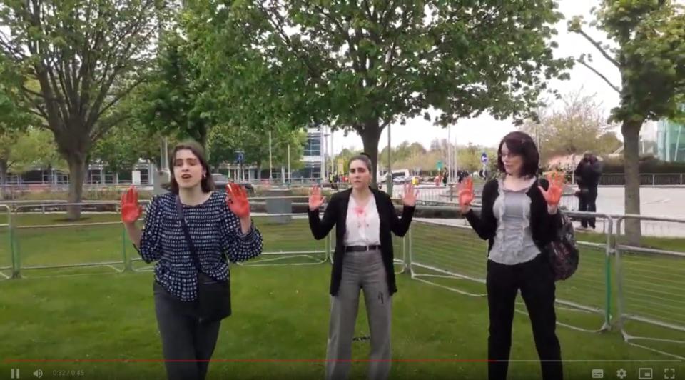 Three protesters disrupt the BP AGM with red paint on their hands, mimicking blood 