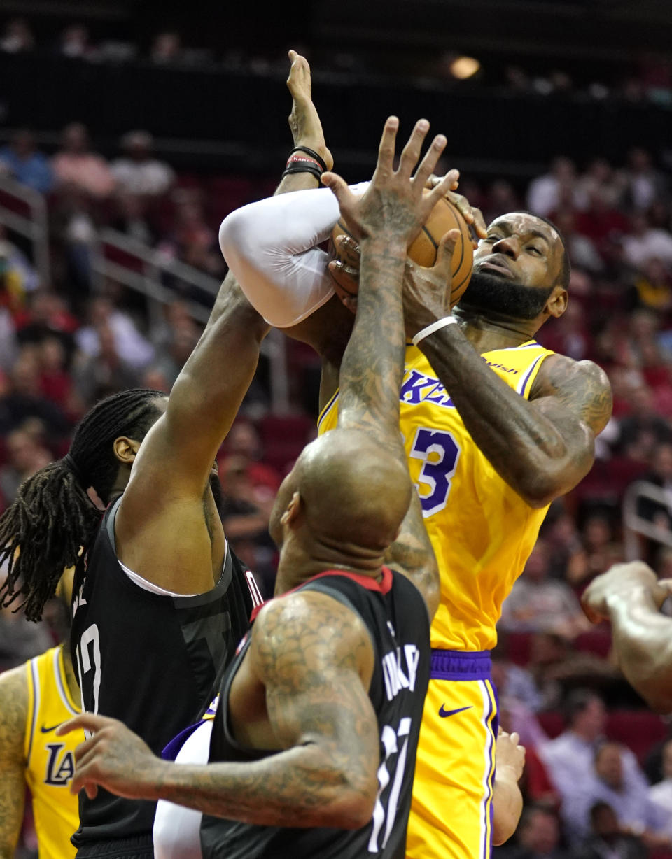 Los Angeles Lakers' LeBron James, right, goes up for a shot as Houston Rockets' Nene Hilario, left, and PJ Tucker, center, defend during the first half of an NBA basketball game Thursday, Dec. 13, 2018, in Houston. (AP Photo/David J. Phillip)