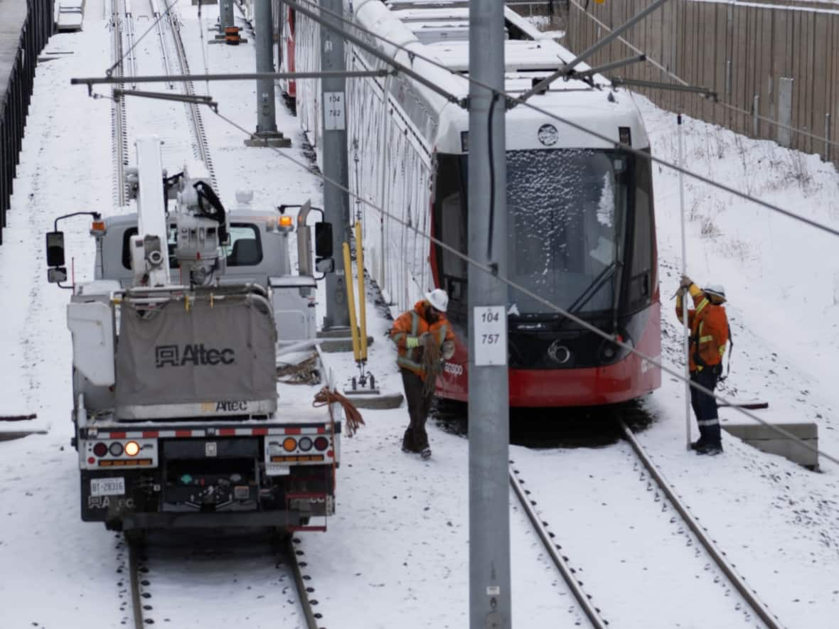 Crews work near a derailed Confederation Line light rail train on Jan. 10, 2023. On Wednesday, city council directed transit services GM Renée Amilcar to negotiate a settlement with LRT builder Rideau Transit Group in an ongoing dispute about whether it had met the requirements of its contract. (Jean Delisle/CBC - image credit)