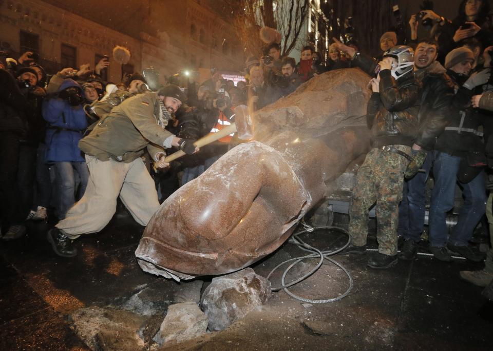 FILE - In this Sunday, Dec. 8, 2013 file photo Ukrainian protesters smash a statue of Vladimir Lenin with a sledgehammer, in central Kiev, Ukraine. After two months of anti-government protests, modern Ukraine has never been so bitterly polarized. To be sure, Ukraine has long been divided. Russia and Europe have vied for dominance for centuries, causing deep cultural differences between the mostly Ukrainian-speaking western and central regions on the one hand, and the Russian-speaking east and south on the other. But as the crisis has deepened, each side has grown stronger in its convictions, and those who stood in the middle have been forced to choose sides. (AP Photo/Efrem Lukatsky, file)