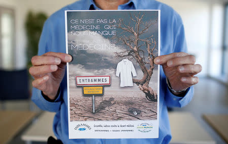 Elected French official Maurice Ciron poses with a poster which reads "It's not medicine we lack, it's the doctors. Entrammes, a village without a doctor" at the city hall in Entrammes, near Laval, France, November 8, 2018. Picture taken November 8, 2018. REUTERS/Stephane Mahe