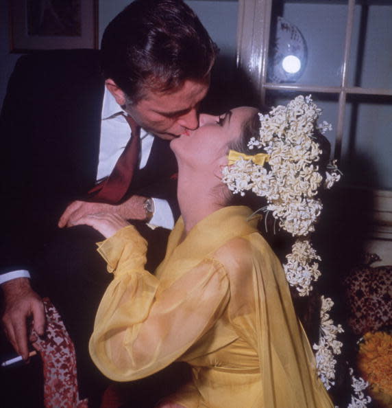 File photo shows Elizabeth Taylor sitting on a sofa kissing her fifth husband, Welsh actor Richard Burton, while he leans over her on their first wedding day. Taylor wore a yellow gown.
