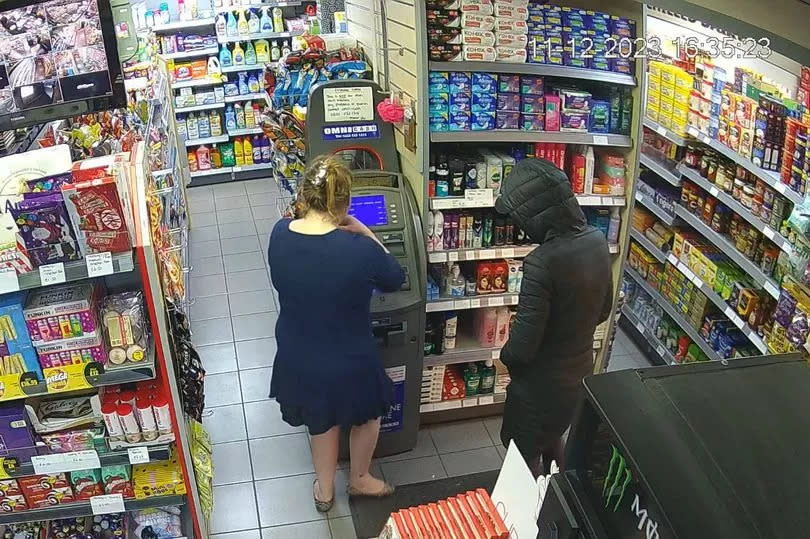 CCTV surveillance still of two woman with back to camera in convenience store at an ATM withdrawing money
