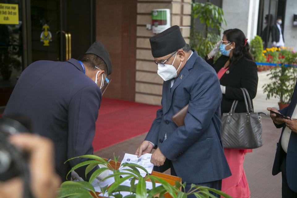 Pushpa Kamal Dahal, leader of the splinter group in the governing Nepal Communist Party shows his COVID-19 test result before entering parliament in Kathmandu, Nepal, Monday, May 10, 2021. Nepal’s prime minister asked parliament for a vote of confidence on Monday in an attempt to show he still has enough support to stay in power despite an expected second split within his governing party. (AP Photo/Niranjan Shrestha)