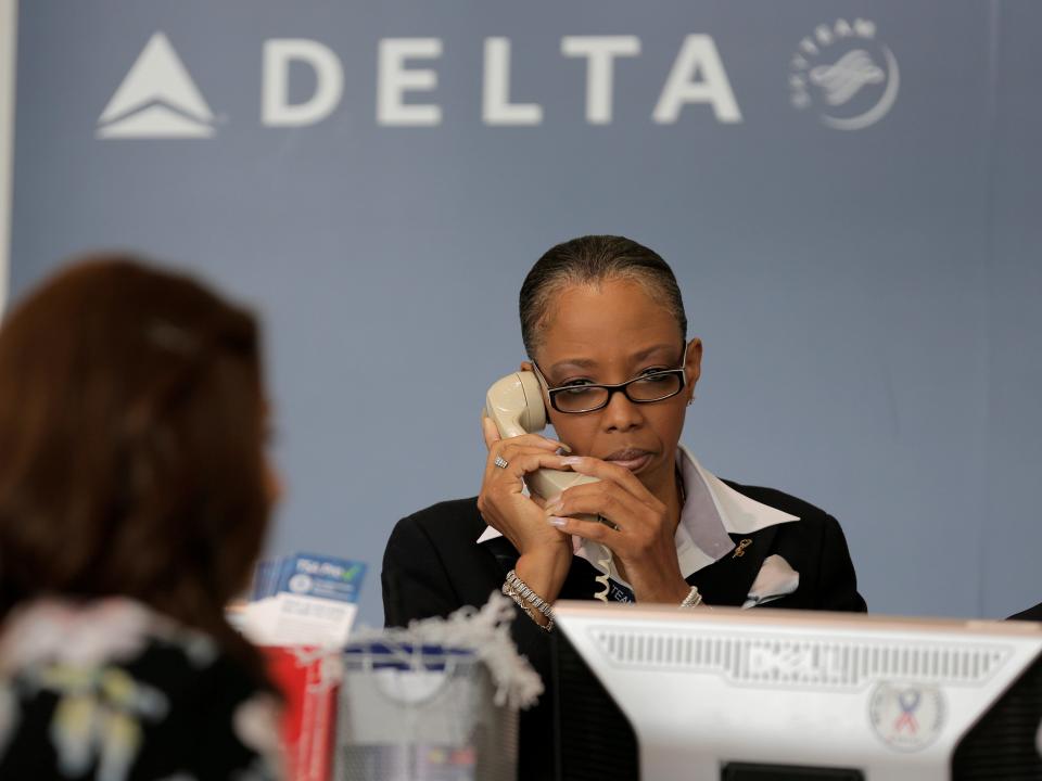 FILE PHOTO: A Delta Airlines ticketing agent assists a passenger after the airlines computer systems crashed leaving passengers stranded as flights were grounded globally at Ronald Reagan Washington National Airport in Washington, U.S., August 8, 2016.      REUTERS/Joshua Roberts    