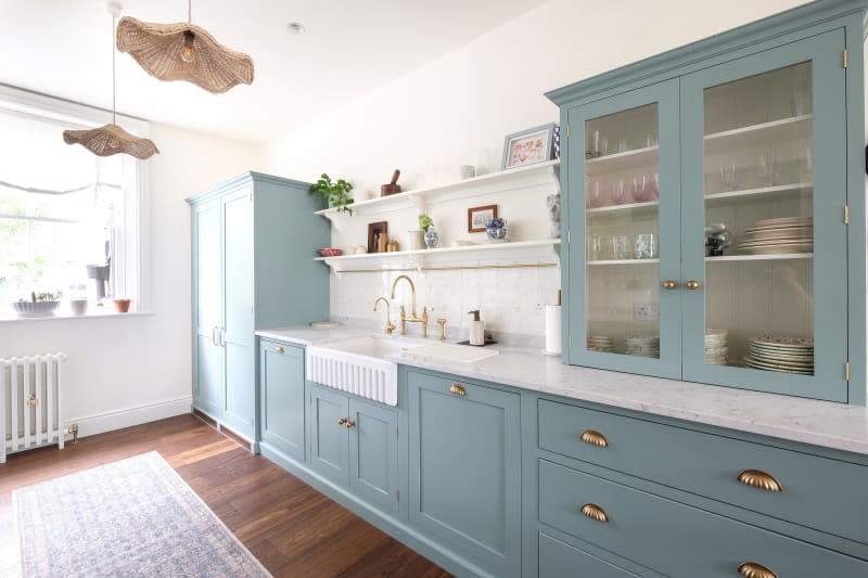 Scalloped pendant lamps in kitchen with blue cabinets and white and gray marbled surface in newly renovated kitchen.