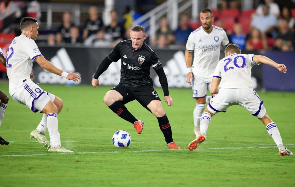 Wayne Rooney dribbles the ball against Orlando City midfielder Oriol Rosell and defender Shane O'Neill, left, during a match Aug. 12, 2018, in Washington. Rooney arrived in America with D.C. United in 2018 at age 32.