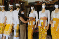 A woman wearing a protective mask prepares to open her traditional Balinese cloth shop in Bali, Indonesia on Friday, May 22, 2020. (AP Photo/Firdia Lisnawati)