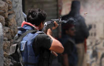 <p>A Pakistani police commando fires at the hideout of alleged criminals during a crackdown operation against criminals in Karachi’s town of Lyari in Pakistan, on April 27, 2012. Criminals and police exchanged fire during the action that killed two person and injured many, security official said. (AP Photo/Shakil Adil) </p>