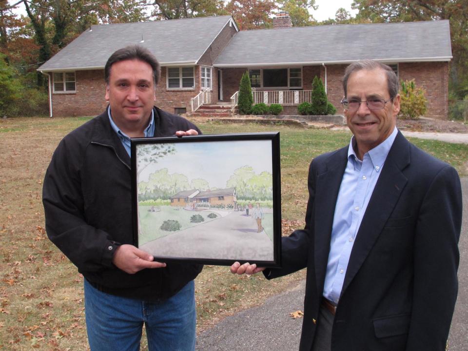 In this Wednesday, Oct. 23, 2013 photo, Steve Fulgoni, left, and Ron Stein, two of the organizers of an effort to restore a home of jazz legend John Coltrane, hold an artist's rendering of the the Dix Hills, N.Y. site after restoration. This is where the saxophonist composed the epic 1964 jazz masterpiece "A Love Supreme." (AP Photo/Frank Eltman)