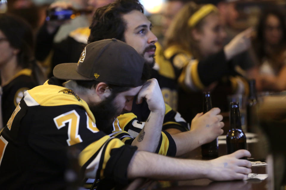 Boston Bruins fan Adam Aldred, front, of Foxborough, Mass., rests his head on his hand at a Boston bar, after the St. Louis Blues defeated the Bruins 4-1 in Game 7 of the NHL hockey Stanley Cup Final, Wednesday, June 12, 2019. (AP Photo/Steven Senne)