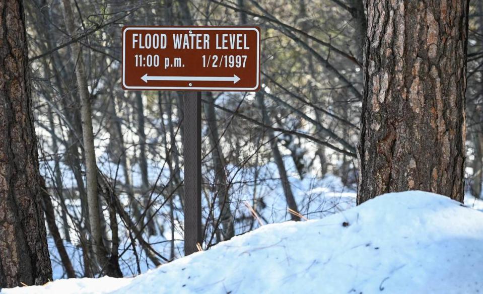 The height of a snowbank nears a sign signifying the flood water level of January 2, 1997 after heavy snowfall, on Friday, March 3, 2023.