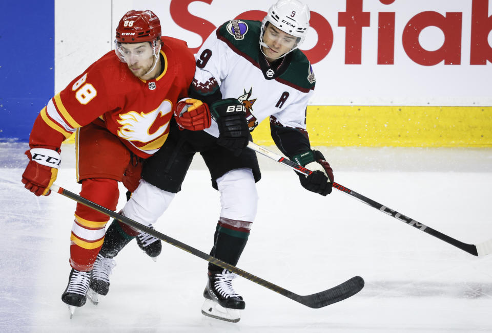 Arizona Coyotes forward Clayton Keller (9) checks Calgary Flames forward Andrew Mangiapane (88) during the first period of an NHL hockey game in Calgary, Alberta, Sunday, April 14, 2024. (Jeff McIntosh/The Canadian Press via AP)