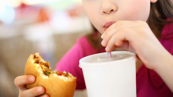 PHOTO: A girl eats a burger with a drink in this undated stock photo. (STOCK PHOTO/Getty Images)