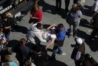 People help a woman who fainted while standing with family members of inmates outside the Topo Chico prison in Monterrey, Mexico, February 11, 2016. REUTERS/Daniel Becerril