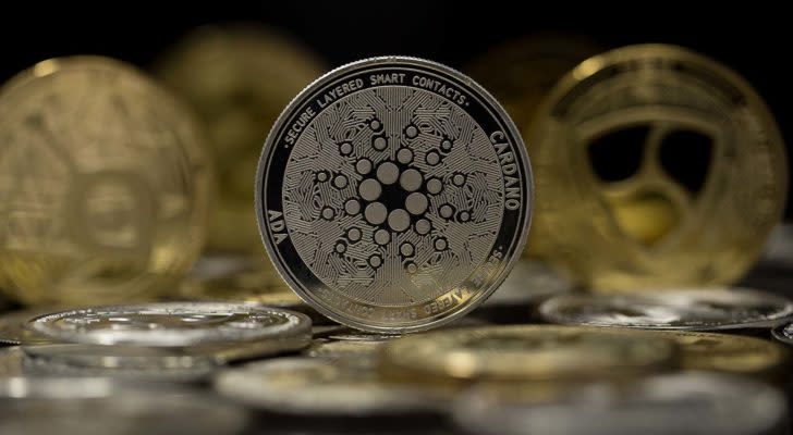 The Cardano (ADA) token with other gold and silver tokens in the background.