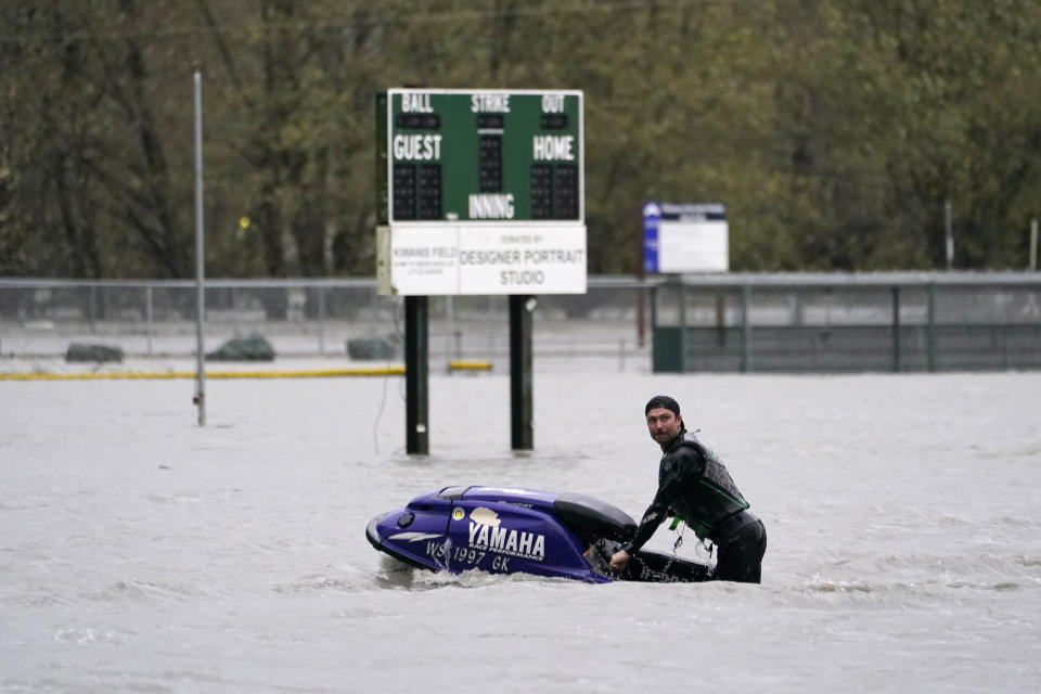 A man operates a personal watercraft in a playfield flooded by water from the Skagit River, Monday, Nov. 15, 2021, in Sedro-Woolley, Wash. (AP Photo/Elaine Thompson)