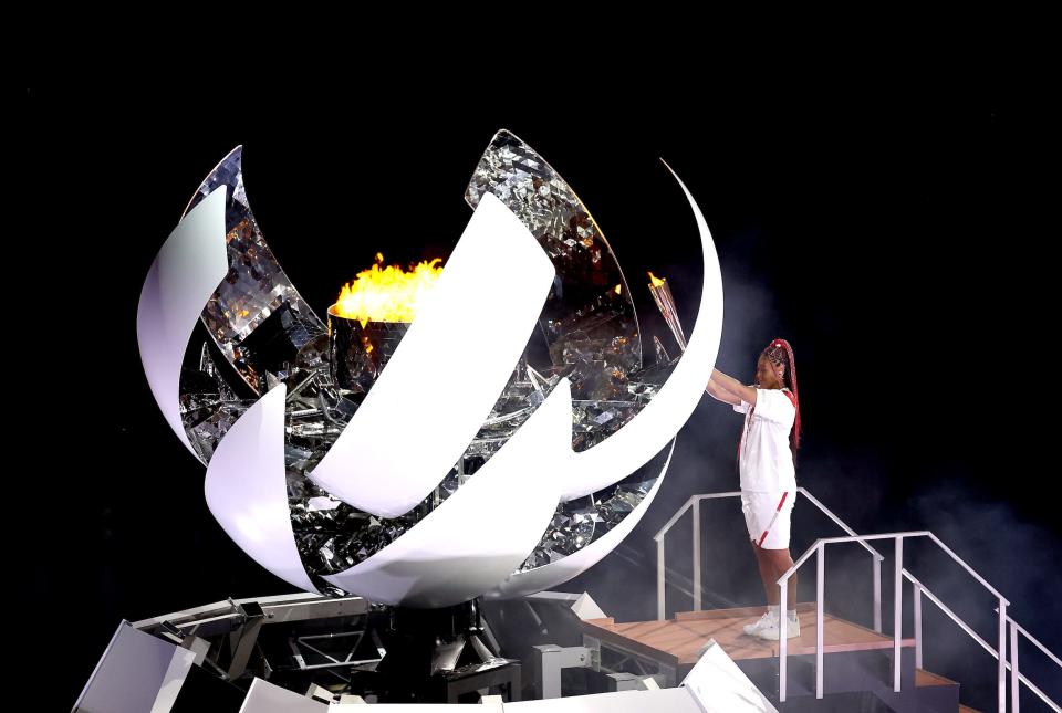 Naomi Osaka of Team Japan lights the Olympic cauldron with the Olympic torch during the opening ceremony.