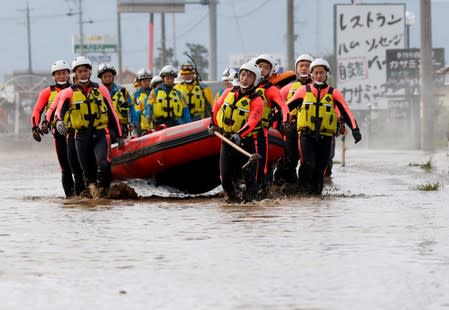 Rescue workers carry a rubber dinghy as they search a flooded area in the aftermath of Typhoon Hagibis, which caused severe floods at the Chikuma River in Nagano