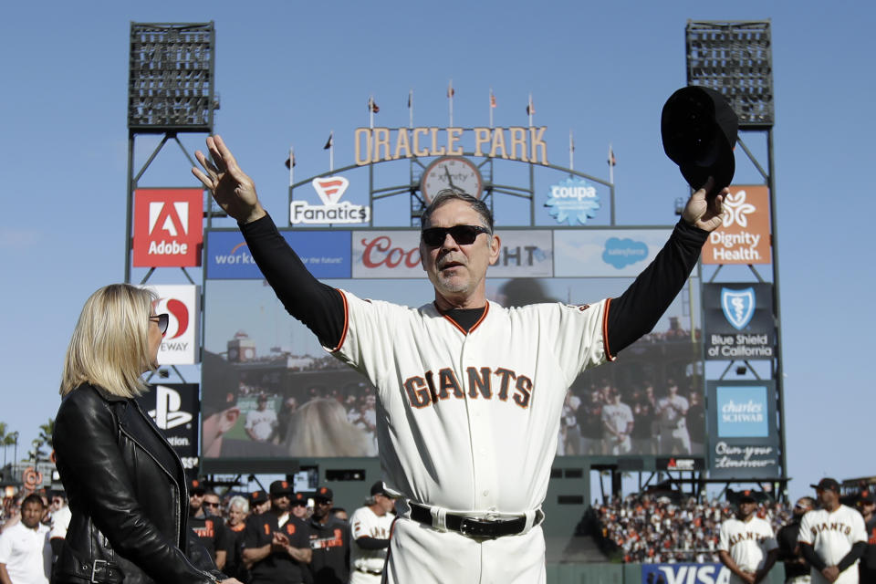 San Francisco Giants manager Bruce Bochy, center, gestures toward fans next to his wife Kim during a ceremony honoring Bochy after a baseball game between the Giants and the Los Angeles Dodgers in San Francisco, Sunday, Sept. 29, 2019. (AP Photo/Jeff Chiu, Pool)