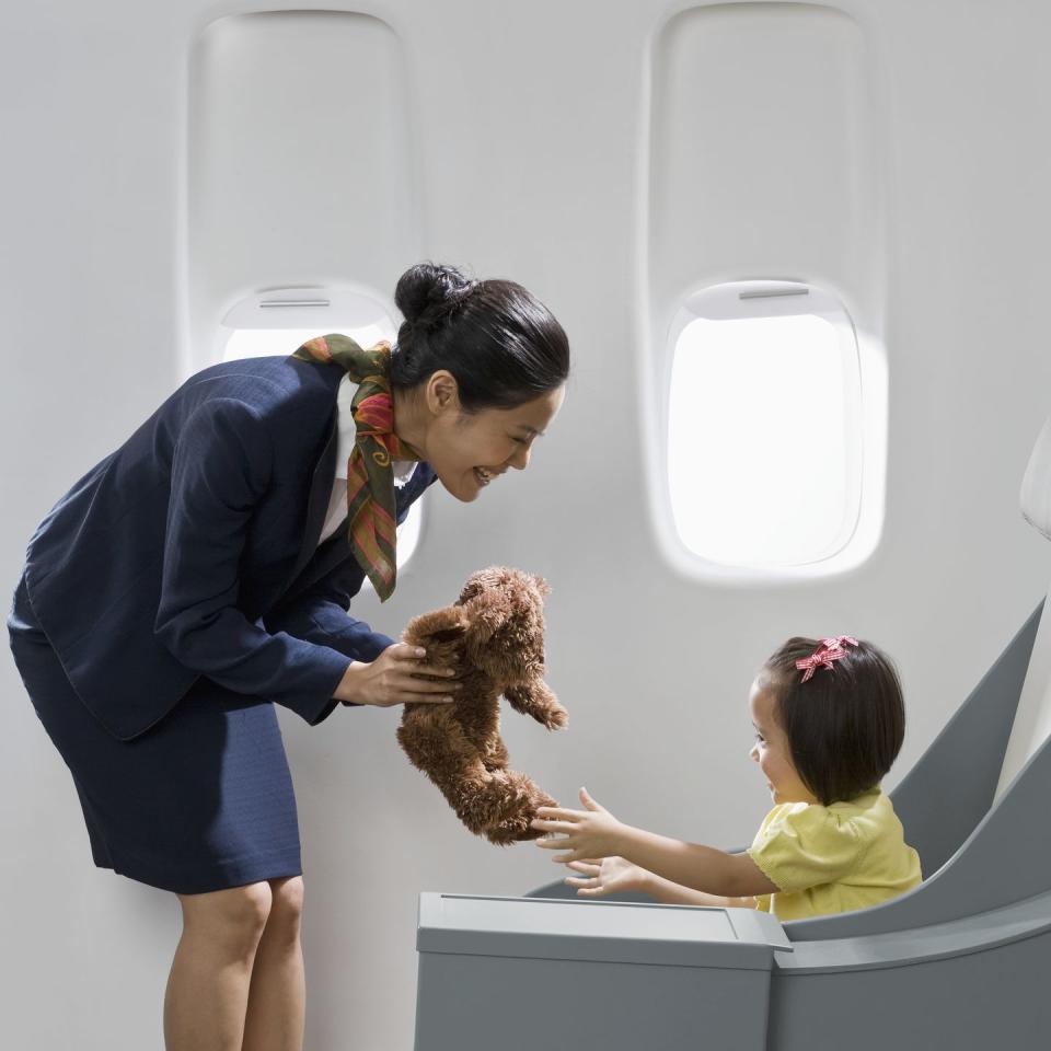 flight attendant giving teddy bear to girl