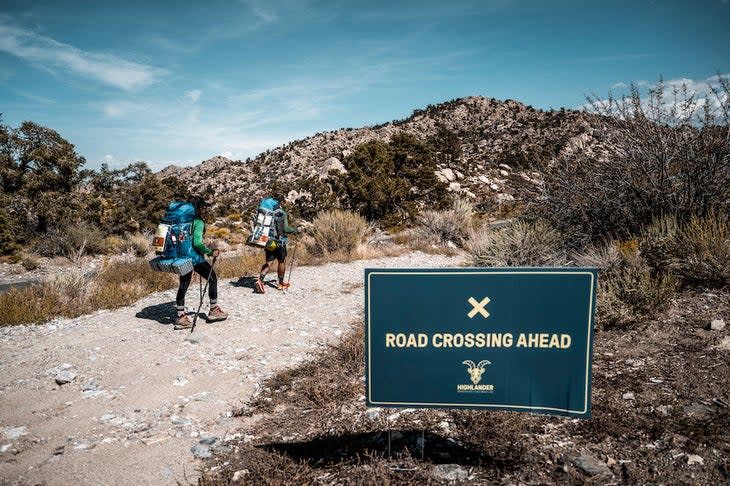 people hiking behind a road crossing sign