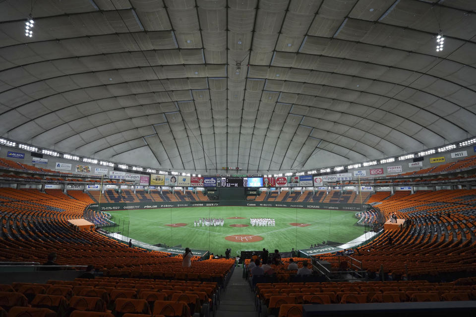 FILE - In this June 19, 2020, file photo, players gather in the empty stands prior to a baseball game between the Yomiuri Giants and the Hanshin Tigers at the Tokyo Dome in Tokyo. Japan’s professional baseball and soccer leagues will begin allowing fans this week, the head of both leagues said on Monday, July 6, 2020. (AP Photo/Eugene Hoshiko, File)