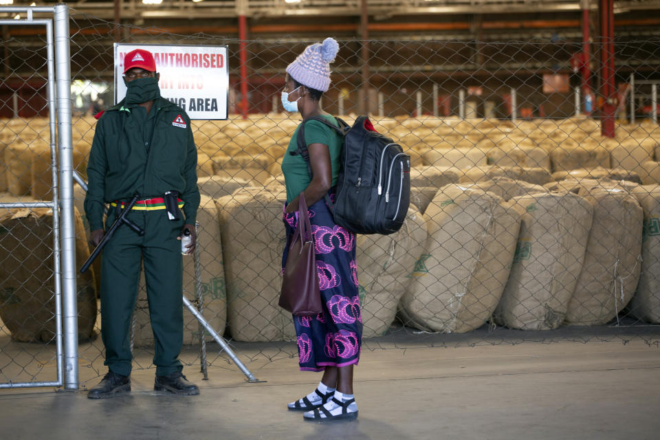 A security guard stands at the entrance of a tobacco auction floor in Harare, Thursday, April 8, 2021. Zimbabwe’s tobacco is flourishing again. And so are the auctions where merchants are fetching premium prices for the “golden leaf” that is exported around the world. Many of the small-scale farmers complain they are being impoverished by middlemen merchants who are luring them into a debt trap. (AP Photo/Tsvangirayi Mukwazhi)