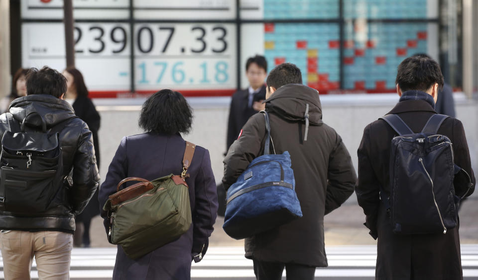 People walk by an electronic stock board of a securities firm in Tokyo, Tuesday, Jan. 21, 2020. Asian stock markets have tumbled as concern about the impact of a Chinese disease outbreak on tourism and regional economies grows. (AP Photo/Koji Sasahara)