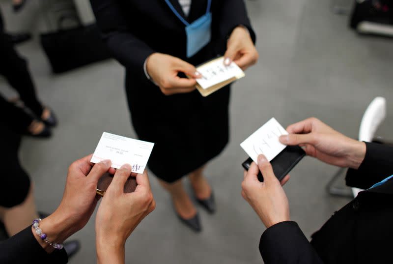 FILE PHOTO : Japanese job-hunting students dressed in suits practice swapping business cards during a business manners seminar at a placement centre in Tokyo