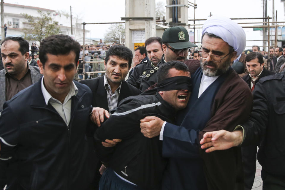 FILE - This Tuesday, April 15, 2014, file picture provided by ISNA, a semi-official news agency, shows Iranian officials and security escorting away the blindfolded man Bilal from the scene of his execution in public in the northern city of Nour, Iran. Bilal, who was convicted of killing Abdollah Hosseinzadeh, was pardoned by the victim's family moments before being executed. The victims mother, Samerah Alinejad, tells The Associated Press that she had felt she could never live with herself if the man who killed her son were spared. But in the last moment, she pardoned him in an act that has made her a hero in her hometown, where banners in the streets praise her family’s mercy. (AP Photo/ISNA, Arash Khamoushi, File)