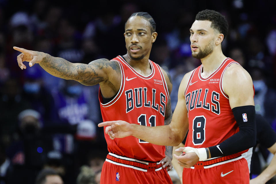 DeMar DeRozan and Zach LaVine of the Chicago Bulls talk to each other while pointing during a game.