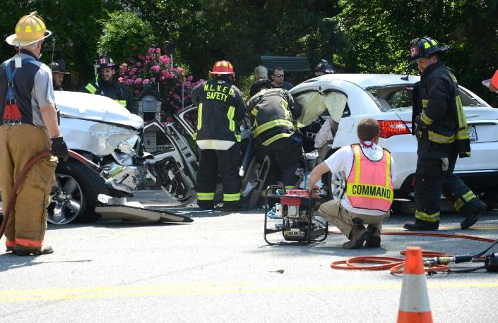 A North Lenoir firefighters remove the driver side door after a woman, pinned in her white vehicle, was rescued using the jaws of life on U.S. 258 North, Tuesday, May 13, 2014, in Kinston, N.C. (AP Photo/Daily Free Press, Janet S. Carter)