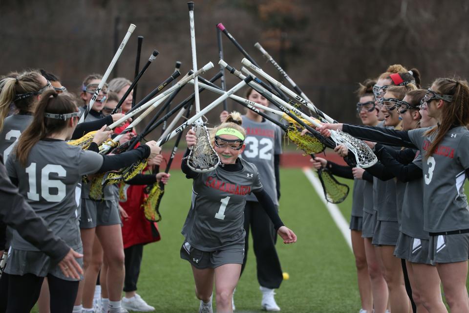 Canandaigua's Hanna Davis (1), center, runs through a tunnel of teammate sticks as she is introduced with the starting lineup before their Section V matchup Monday, March 4, 2022 at Our Lady of Mercy in Brighton. 