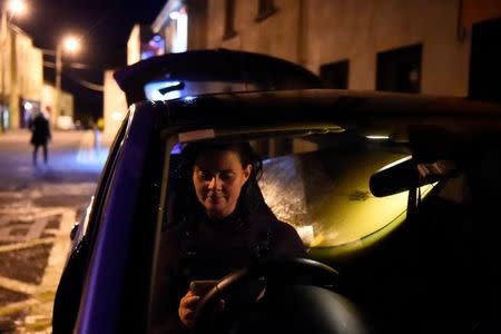 A surfer uses her mobile phone in her car after surfing in the Atlantic ocean on the eve of storm Ophelia in the County Clare town of Lahinch, Ireland October 15, 2017. REUTERS/Clodagh Kilcoyne