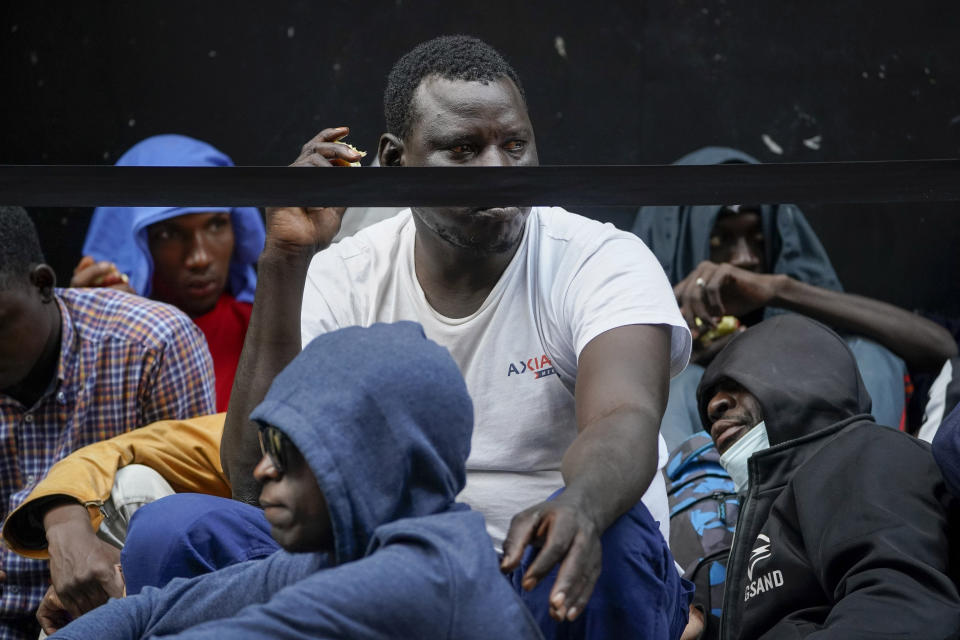 Migrants sit in a queue outside of The Roosevelt Hotel that is being used by the city as temporary housing, Monday, July 31, 2023, in New York. (AP Photo/John Minchillo)