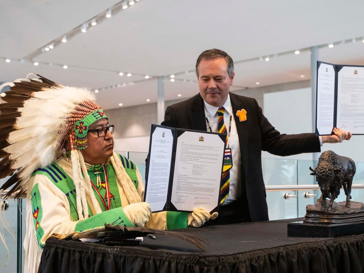 Elder Leonard Bastien, left, and Alberta Premier Jason Kenney, sign a co-stewardship agreement as they announce a new path forward regarding the stewardship of Manitou Asinîy, in Edmonton, on Friday. (Jason Franson/The Canadian Press - image credit)