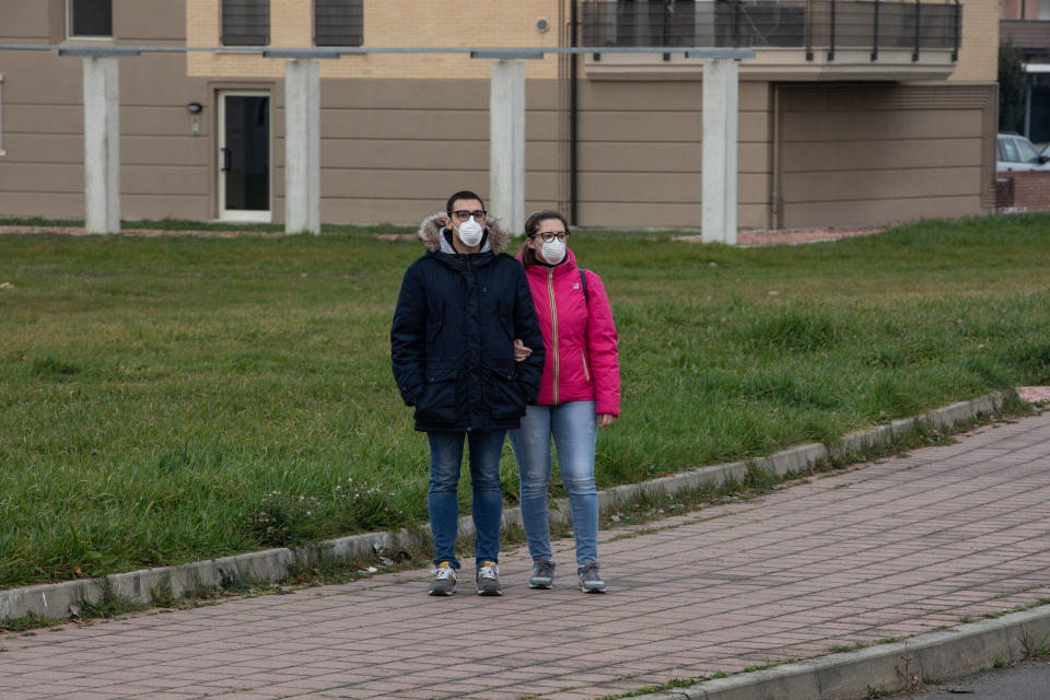 CASALPUSTERLENGO, ITALY - FEBRUARY 23: A couple, wearing a respiratory mask, stands on February 23, 2020 in Casalpusterlengo, south-west Milan, Italy. Casalpusterlengo is one of the ten small towns placed under lockdown earlier this morning as a second death from coronavirus sparked fears throughout the Lombardy region. (Photo by Emanuele Cremaschi/Getty Images)