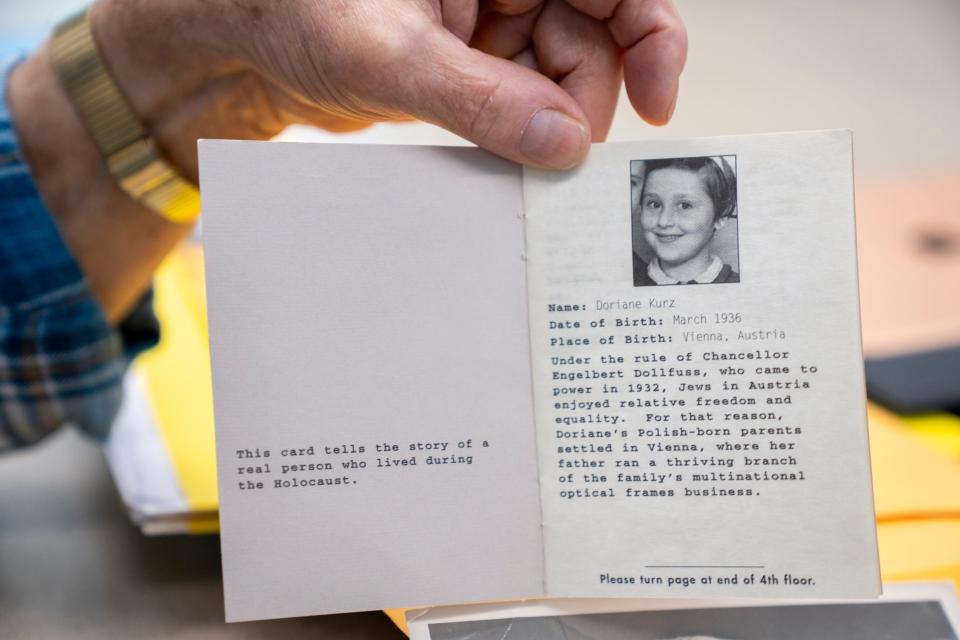 Fred Kurz holds up a mock identification card of his sister, Doriane, from the U.S. Holocaust Memorial Museum.