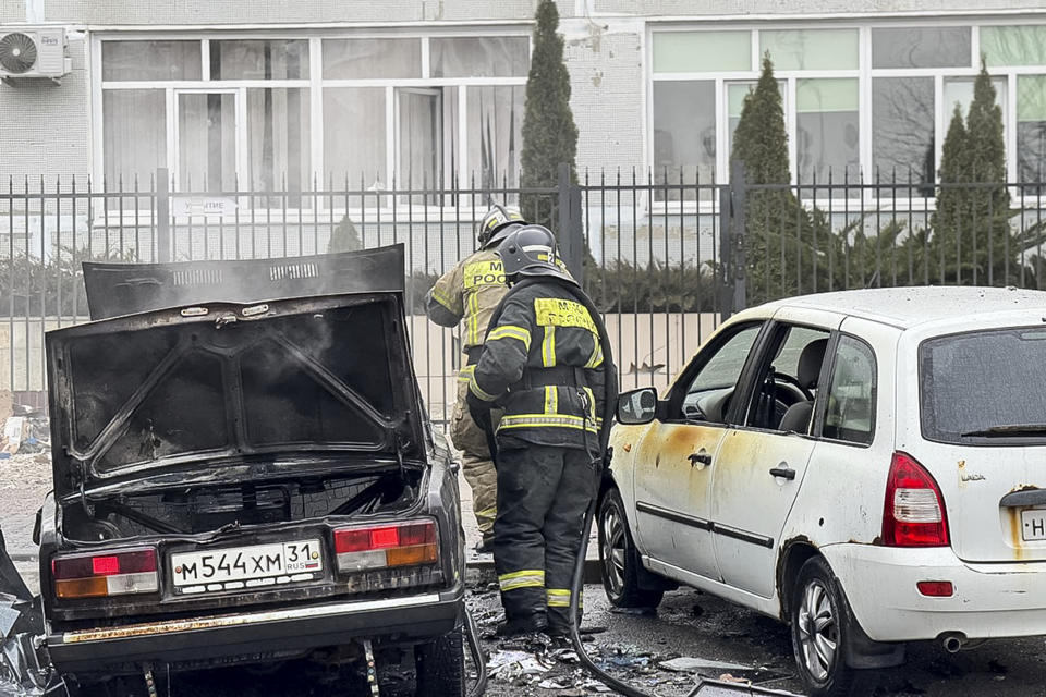 This photo released by Belgorod region governor Vyacheslav Gladkov's telegram channel on Saturday, March 16, 2024, shows emergency employees working by damaged and burned cars after shelling from the Ukrainian side, in Belgorod, Russia. A Russian regional governor says two people have been killed in Ukrainian shelling of the city of Belgorod, close to the border with Ukraine. Three others were wounded. (Belgorod region governor Vyacheslav Gladkov telegram channel via AP)