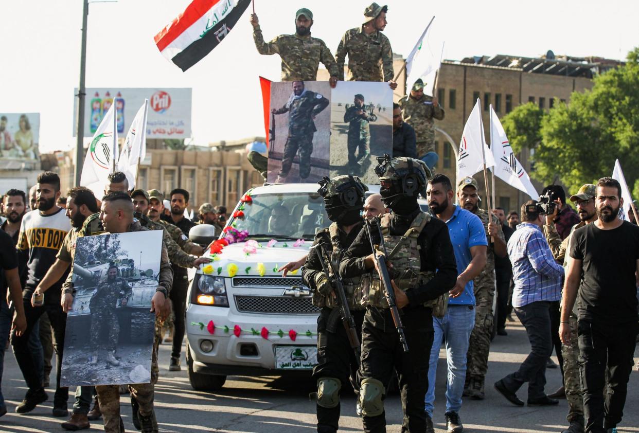 Members of the Hashed al-Shaabi, or Popular Mobilisation Forces (PMF), paramilitaries walk in a funerary procession next to a vehicle carrying the body of Wissam Alyawi, a leading commander of the Asaib Ahl Al-Haq faction that is part of the PMF, in the Iraqi capital Baghdad on October 26, 2019: Photo by AHMAD AL-RUBAYE/AFP via Getty Images)