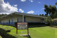 A sign at Pauoa Elementary School in Honolulu on Monday, August 17, 2020, informs students when to pick-up computers for distance learning. Many Hawaii public school students are spending the first day of school online as coronavirus cases surge, mostly on the island of Oahu, where Honolulu is located. (AP Photo/Jennifer Sinco Kelleher)